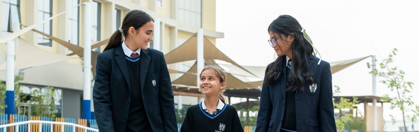 Senior pupils walking across the campus with a younger pupil