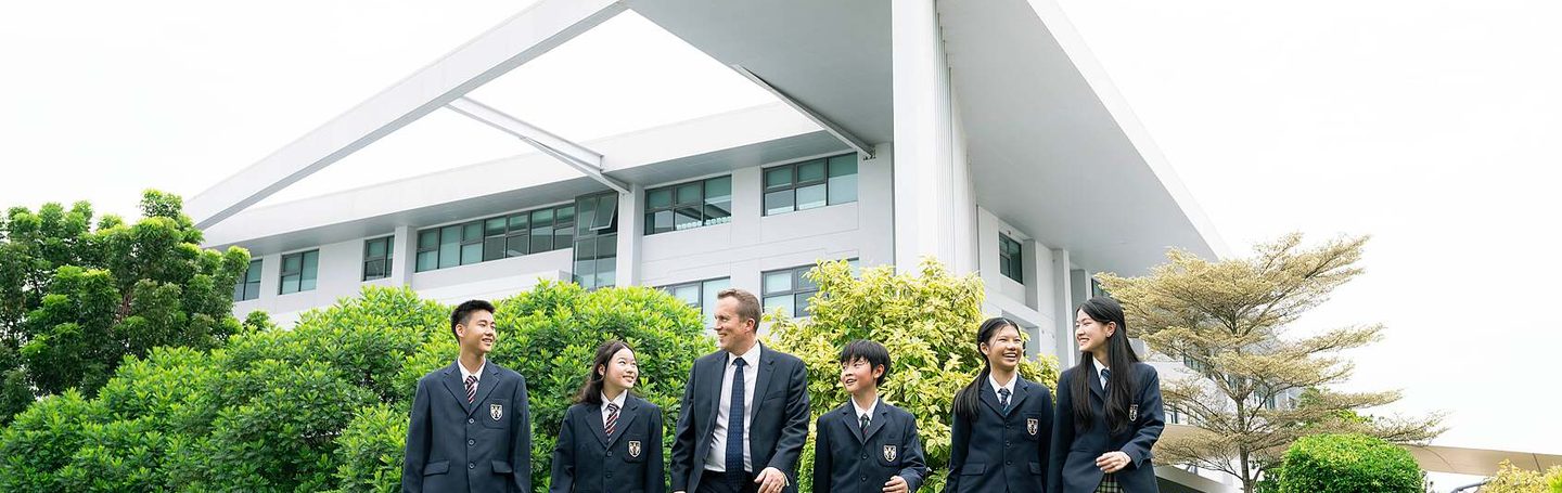 Senior pupils with a teacher outside the school building